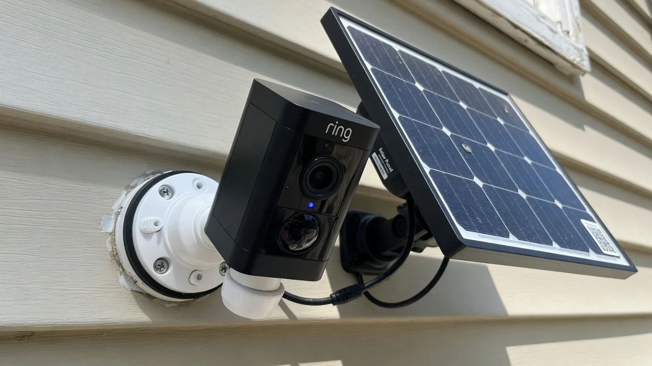 Close-up of a Ring camera powered by a solar panel mounted on house siding